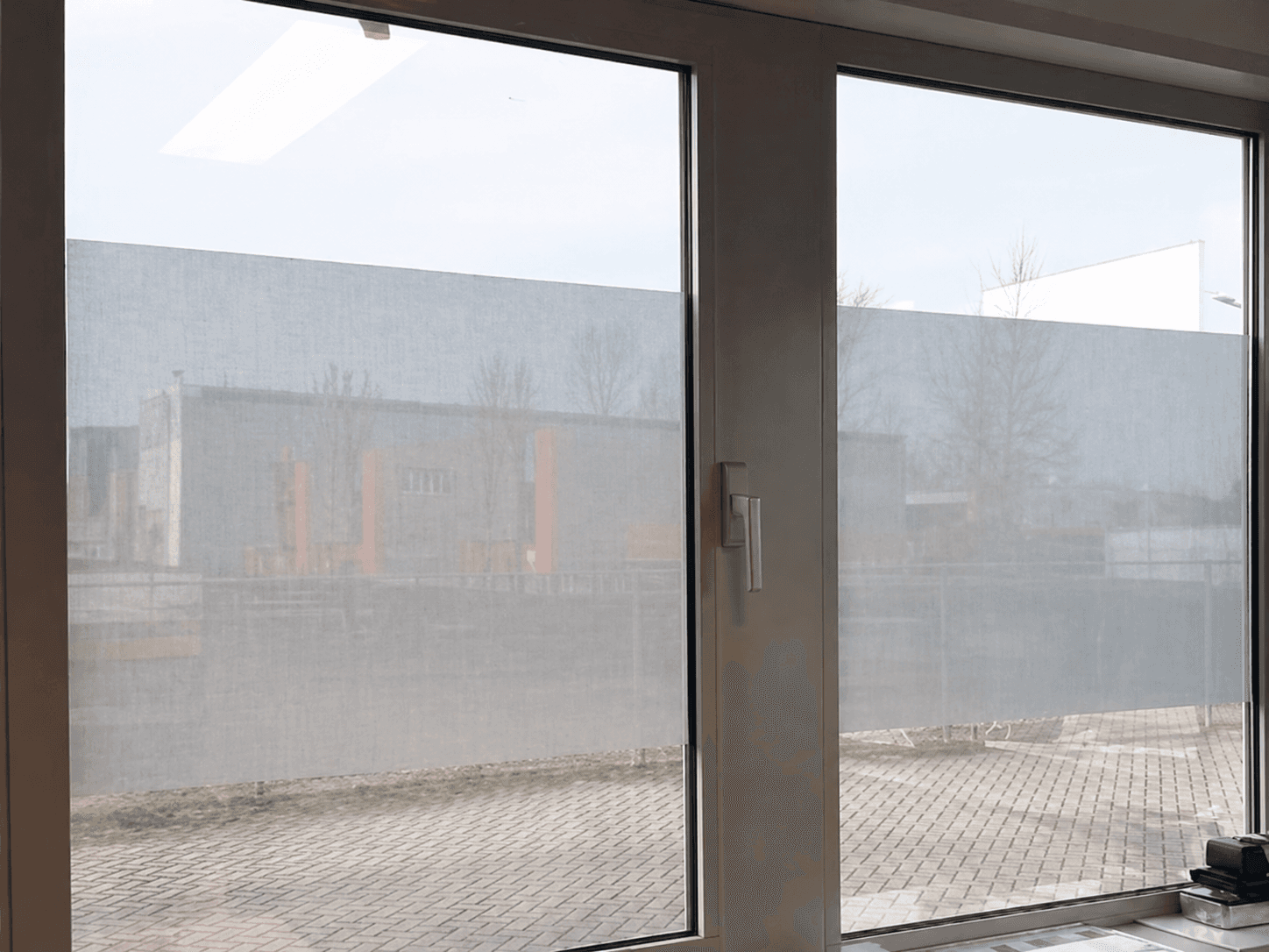 Matte raamfolie op grote kantoorramen met aluminium kozijnen, toegepast als horizontale privacyfolie met behoud van lichtinval.