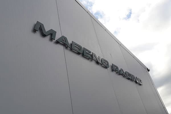 Witte gevel van een bedrijfspand met donkere 3D gevelletters "MADERO RACING" hoog gemonteerd als strakke gevelreclame.