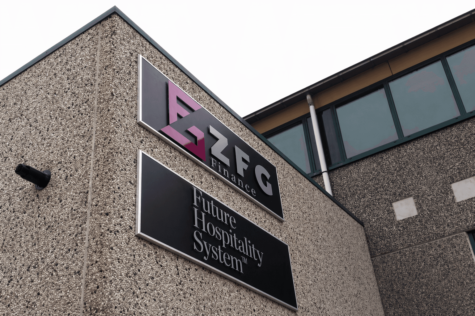 Twee gevelborden op een grindbetonnen bedrijfspand met RFG Finance-logo en de tekst Future Hospitality System op donkere panelen.