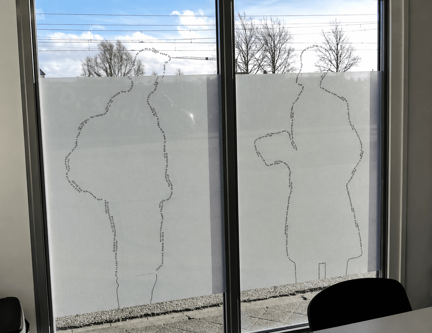 Matte raamfolie op kantoorramen met decoratieve silhouetcontouren, toegepast als privacyfolie met behoud van daglicht en zicht naar buiten.