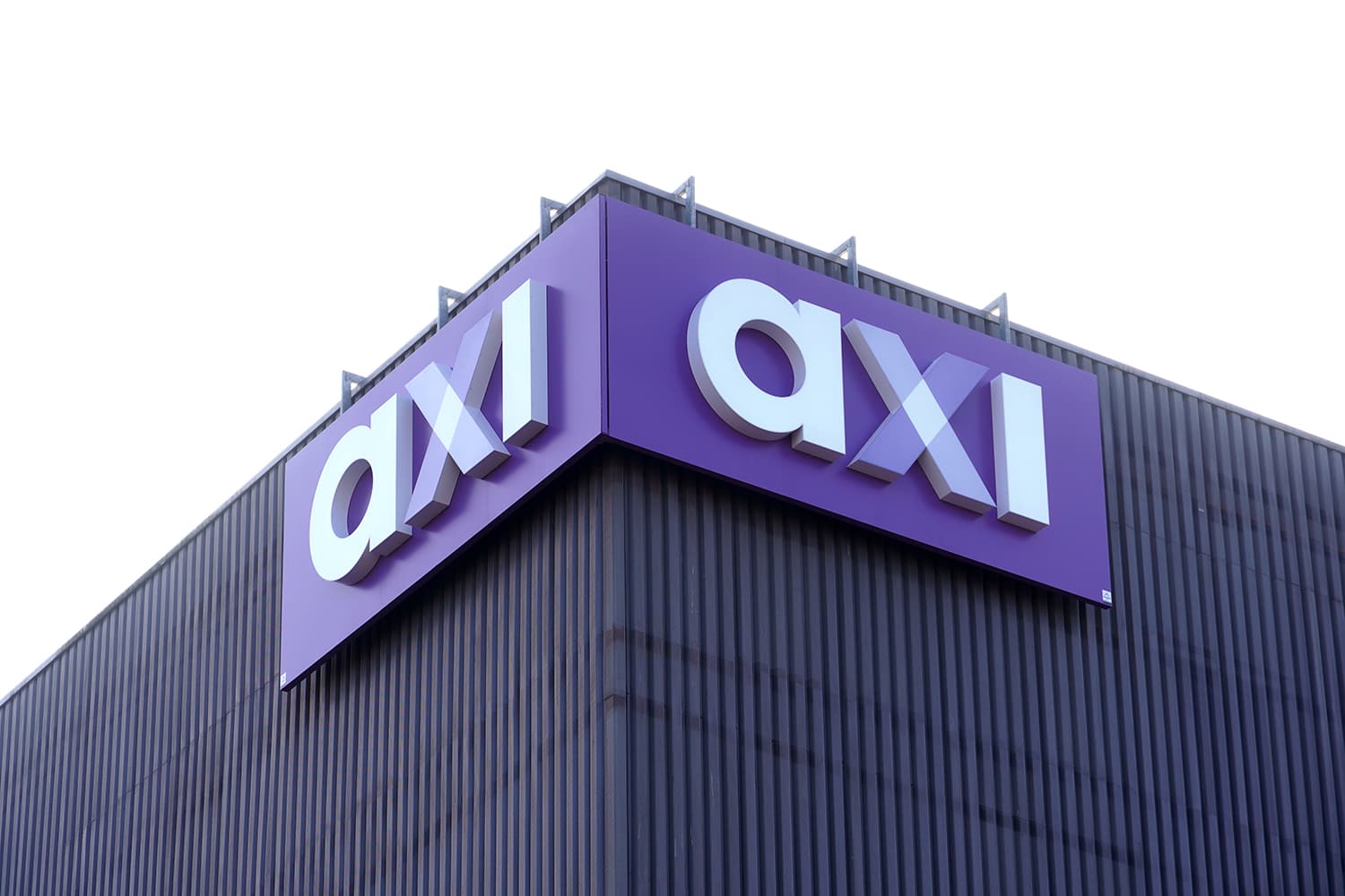 Paarse hoekgevelreclame met witte 3D doosletters "axi" gemonteerd op de donkere metalen gevel van een modern bedrijfspand.